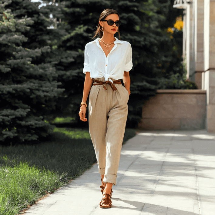 Fashionable woman walking in a stylish outfit featuring a white shirt and beige trousers.
