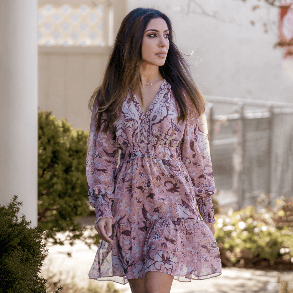 Model wearing a floral pink dress, showcasing elegance and style during a sunny day.