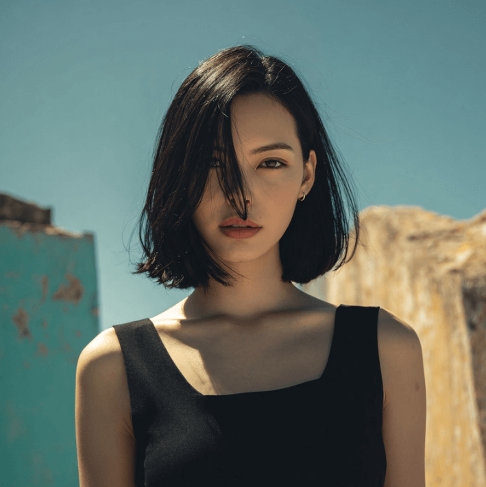 Model showcasing radiant skin with a short bob hairstyle under a clear sky for Ultra Lift Serum.