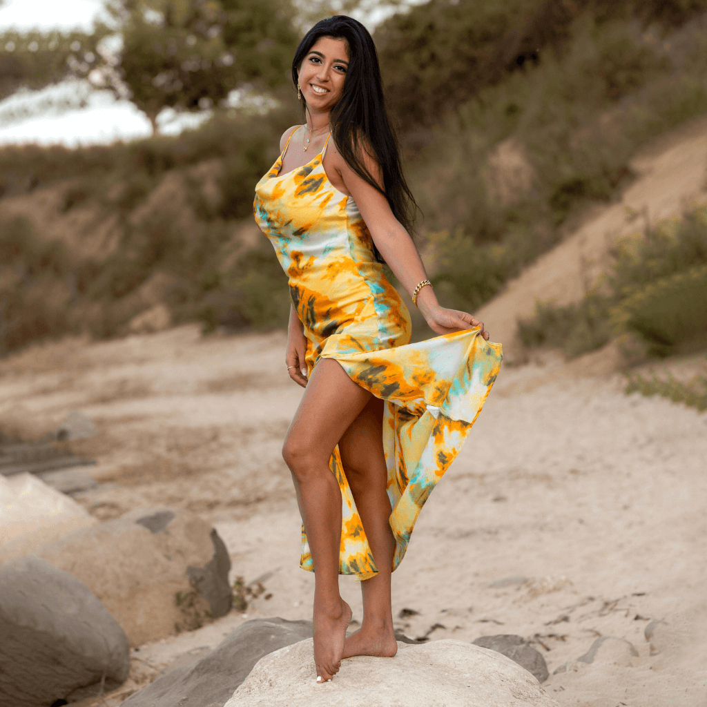 Optimaal in een kleurrijke jurk, poseert een vrouw op het strand met een frisse uitstraling.